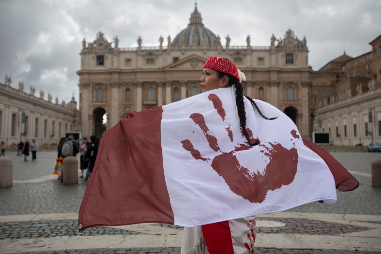 A photo of Lorelei Williams wearing a flag depicting a red hand print instead of a maple leaf on the Canadian flag.