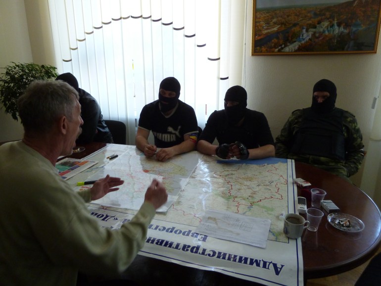 Masked separatists listen to an average Donetsk resident in a city hall office