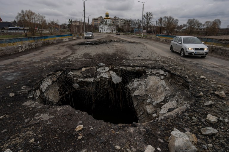 Cars drive near a damaged bridge following Russian attack in the town of Makarov, Kyiv region.