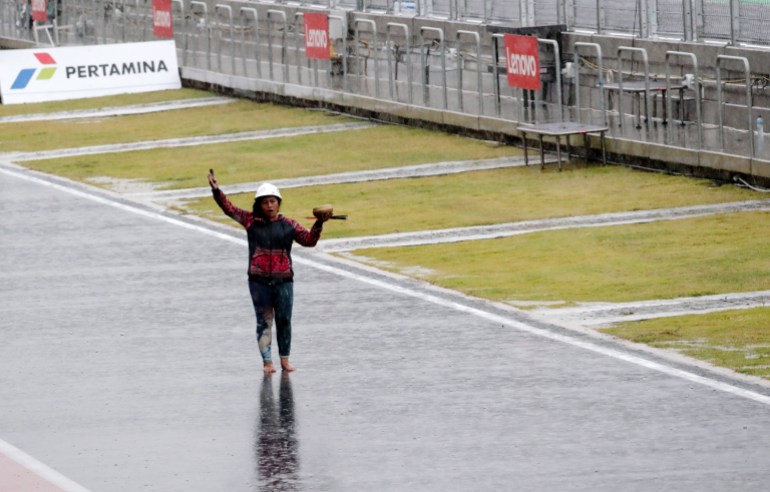 Rara Istiati Wulandar takes to the circuit barefoot during a thunderstorm in an attempt to move the rain away 