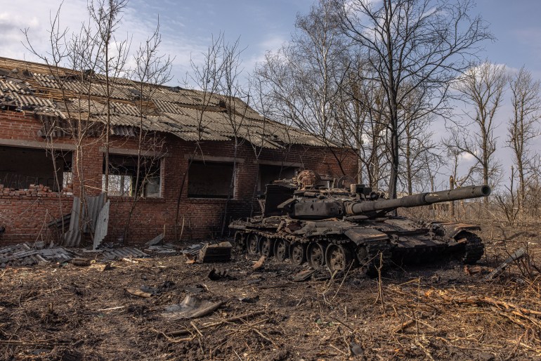 A destroyed Russian tank, next to damaged houses in the recaptured by the Ukrainian army Mala Rohan village, near Kharkiv