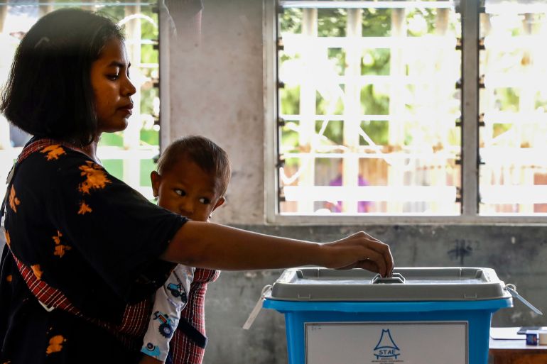 A woman casts her vote in TImor Leste's election while holding her child