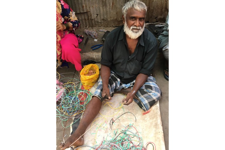 A waste picker is picking the copper from wires in Mumbai, India