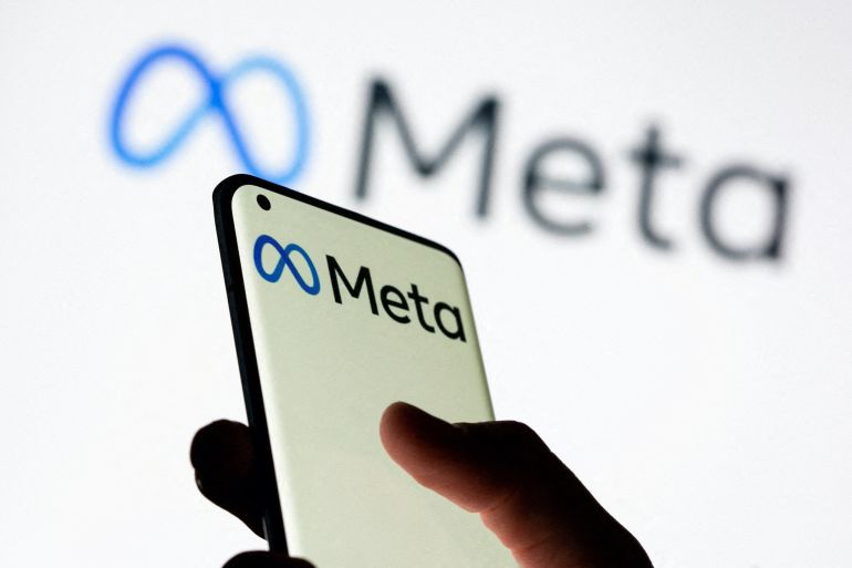 Woman holds smartphone with Meta logo in front