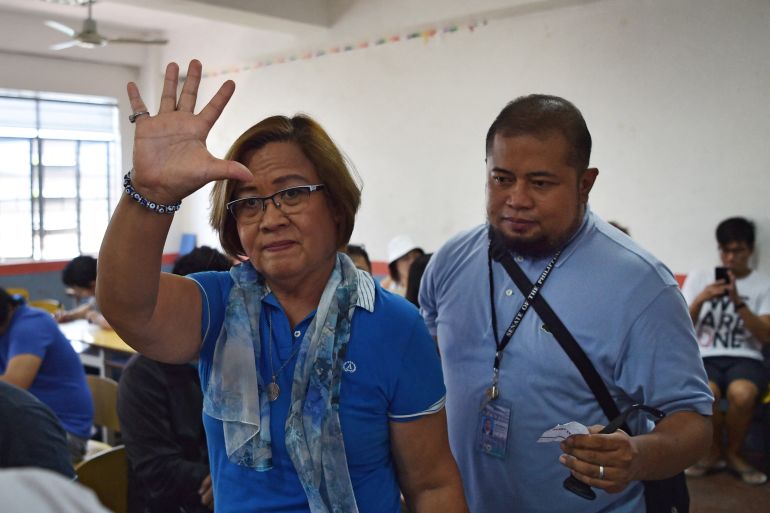 Detained opposition Senator Leila de Lima (walking left) waves to supporters as she is escorted from detention to vote in 2019)