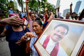 A woman loyal to Rajapaksa carries his portrait during protests outside his official residence