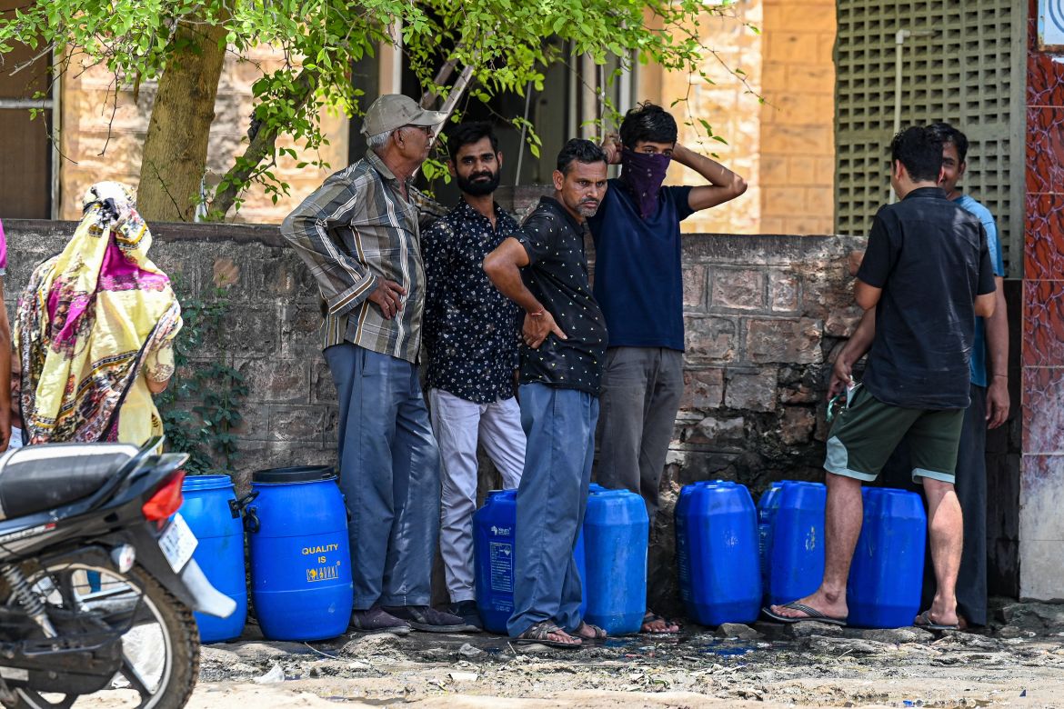 People waiting to refill their containers with tap water supplied by the government on a hot summer day in Pali. -