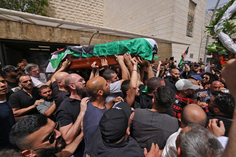 Palestinian mourners carry the coffin of slain Al Jazeera journalist Shireen Abu Akleh out of a hospital, before being transported to a church and then her resting place, in Jerusalem
