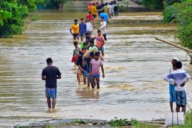 Villagers wade through a flooded road after heavy rains in Hojai district of India's Assam