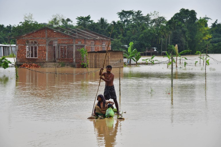 Villagers make their way on a raft past homes in a flooded area after heavy rains in Nagaon district, Assam state, India