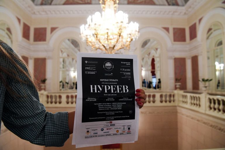 A woman holds a poster announcing the "Nureyev" ballet premiere at the Bolshoi theatre hall.