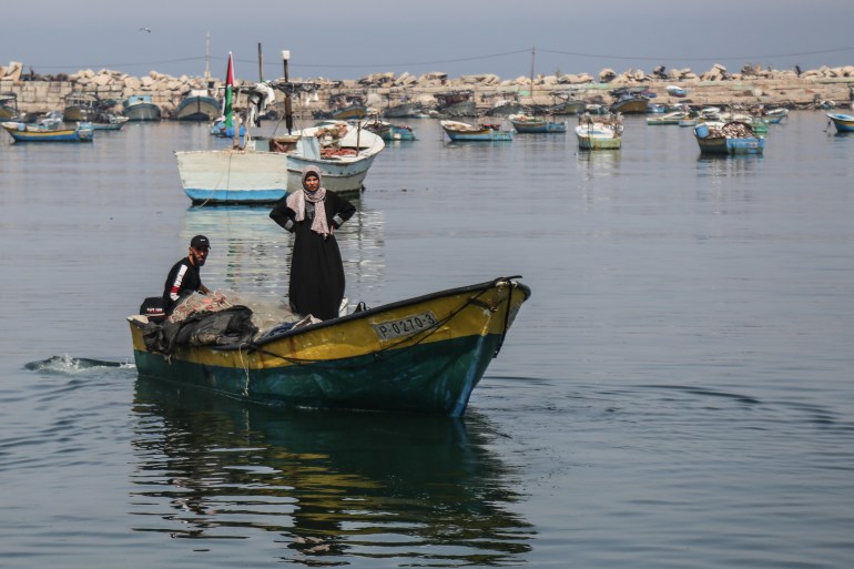 Photo of Madelyn standing in their fishing boat while Khadr steers it