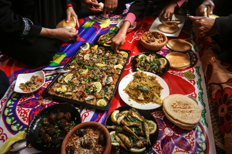 A side-angle view of the dishes and people's hands reaching out to eat