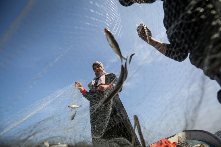 A view of Madelyn through fishing nets as she sorts them