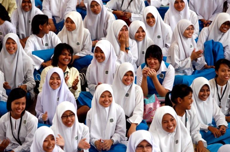 Young Malaysian girls including Muslim Malays, ethnic Indians and Chinese sit in a school hall in their uniforms