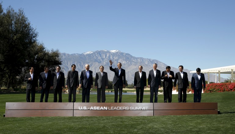Barack Obama waves to photographers during a 'family photo' with ASEAN leaders on the grass at Sunnylands with mountains behind