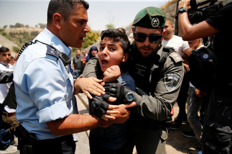 A Palestinian youth is detained by an Israeli border police officer