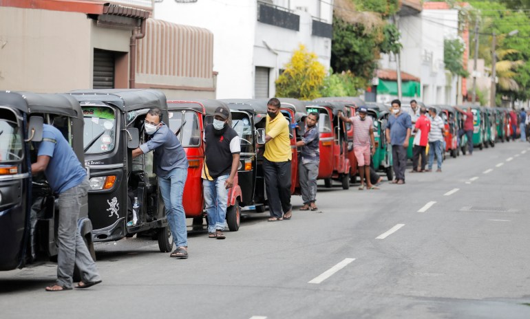 People wait in a queue to buy petrol at a fuel station