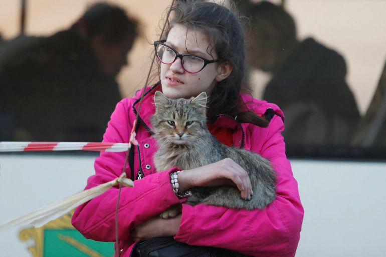 A girl holds a cat next to a bus before departing from a temporary accommodation centre for evacuees during Ukraine-Russia conflict in the village of Bezimenne in the Donetsk Region, Ukraine May 1, 2022. REUTERS/Alexander Ermochenko