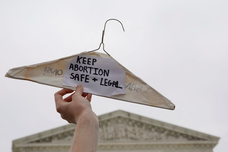 A pro-abortion rights demonstrator holds up a clothes hanger during a protest outside the U.S. Supreme Court