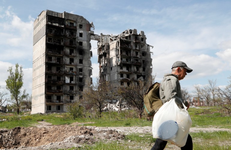 A man is seen walking near a destroyed residential building in Mariupol