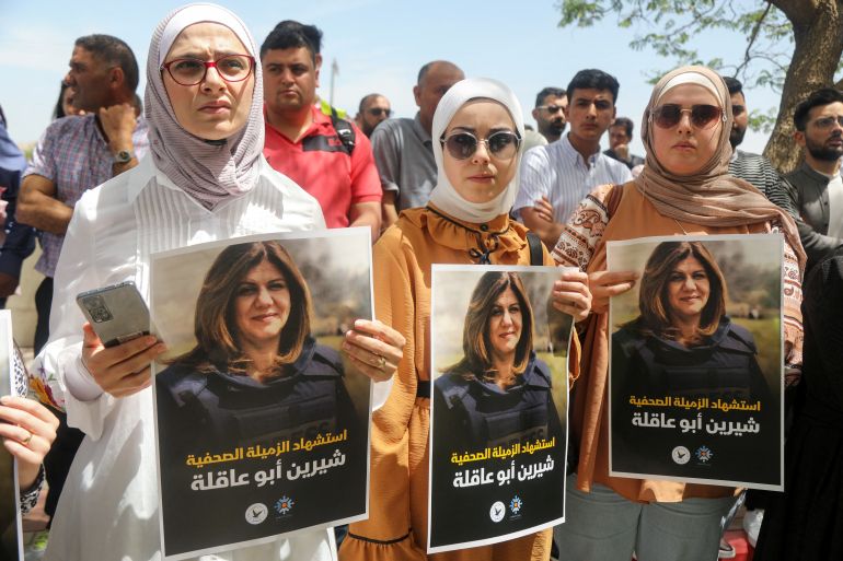 Palestinian women hold pictures of Al Jazeera reporter Shireen Abu Akleh
