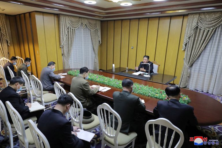 Kim Jong Un speaks behind a large desk to staff at the pandemic emergency headquarters