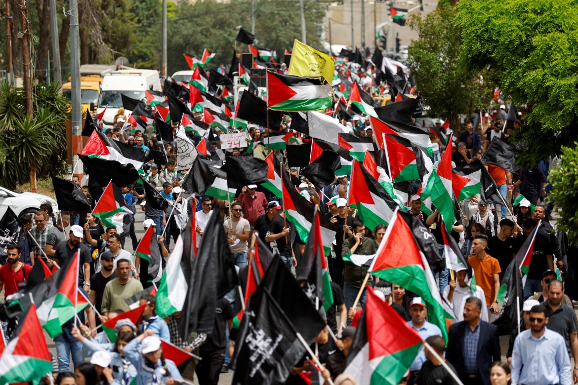 Palestinian wave national flags as they march in a rally marking the 74th anniversary of the "Nakba" or "catastrophe"