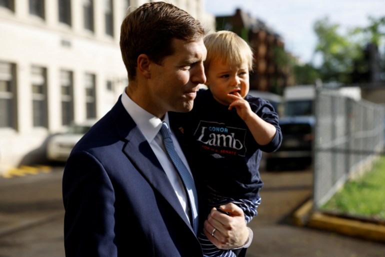 Democratic Party U.S. Senate candidate Rep. Conor Lamb speaks to reporters while holding his son, Matthew, at a polling station in Pittsburgh, Pennsylvania,.