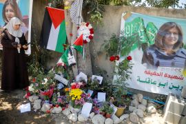 Tree where Shireen Abu Akleh was shot with impromptu shrine of flowers and photos.