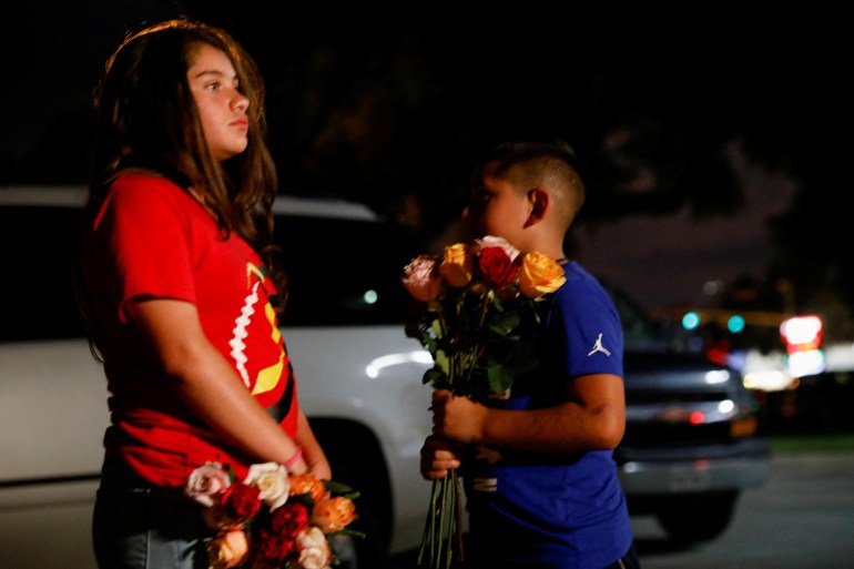 A girl (left) and boy (right) hold flowers in the aftermath of the Robb Elementary School shooting