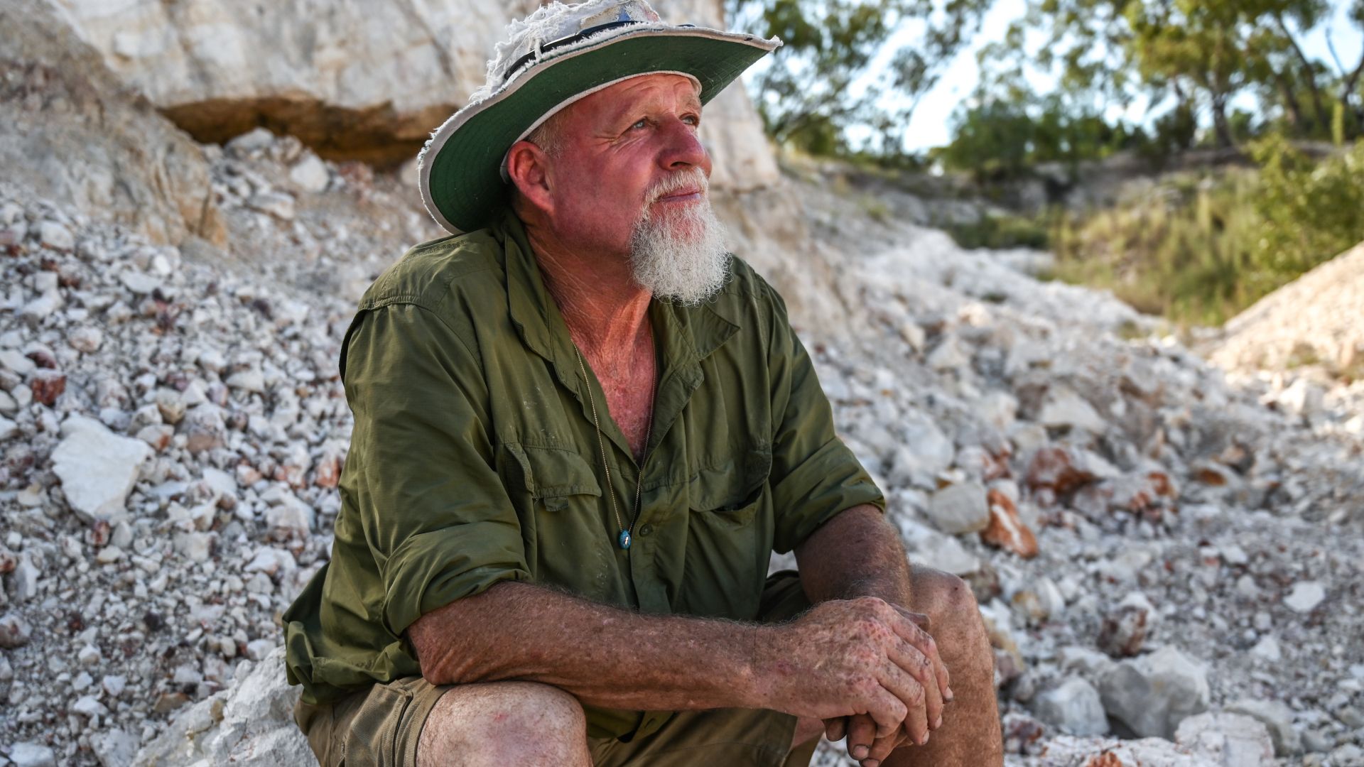 A photo of Pete Cooke sitting on rocks.