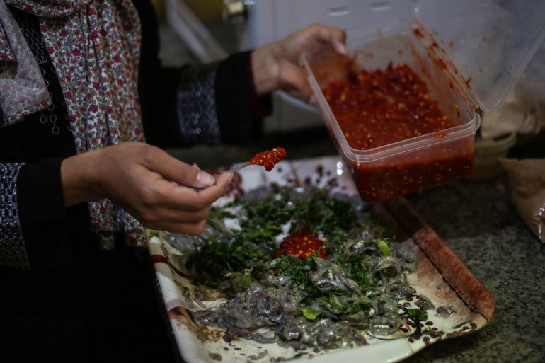 Madelyn's hands are shown as she spoons red pepper paste into a shallow bowl of sardines mixed with seasonings