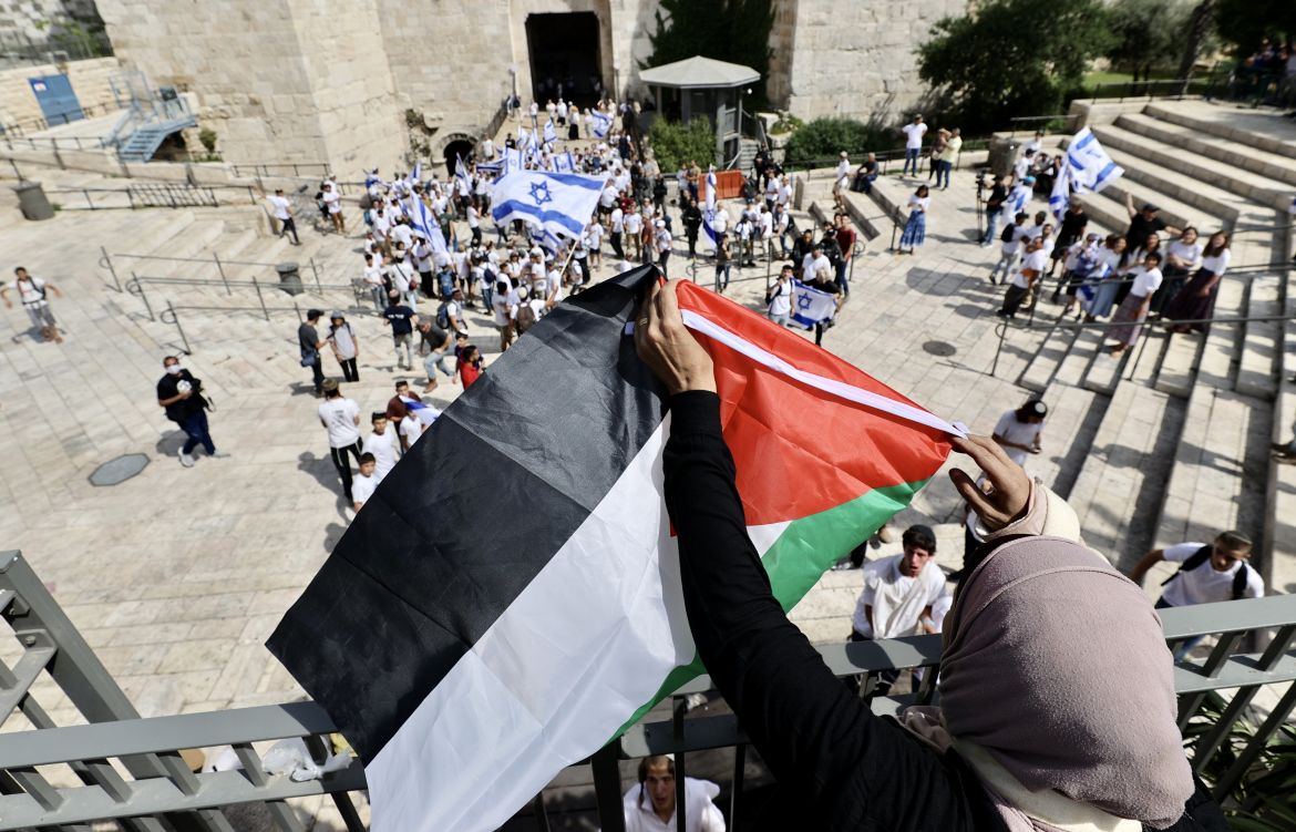 A Palestinian woman reacted to the march by unfurling the Palestinian flag.