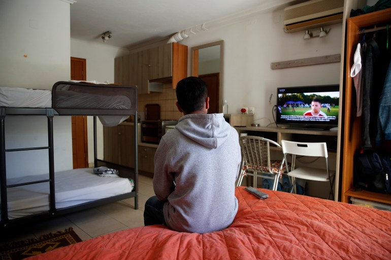 An Afghan father watches television in his room, at the port of Vathy on the eastern Aegean island of Samos, Greece