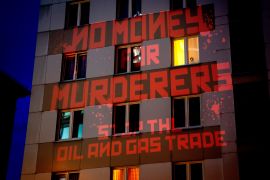 A sign saying "No Money for Murderers, Stop the Oil and Gas Trade"
