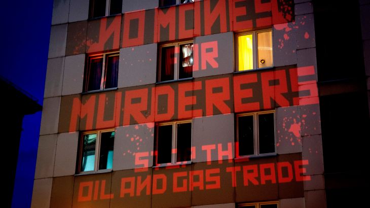 A sign saying "No Money for Murderers, Stop the Oil and Gas Trade"