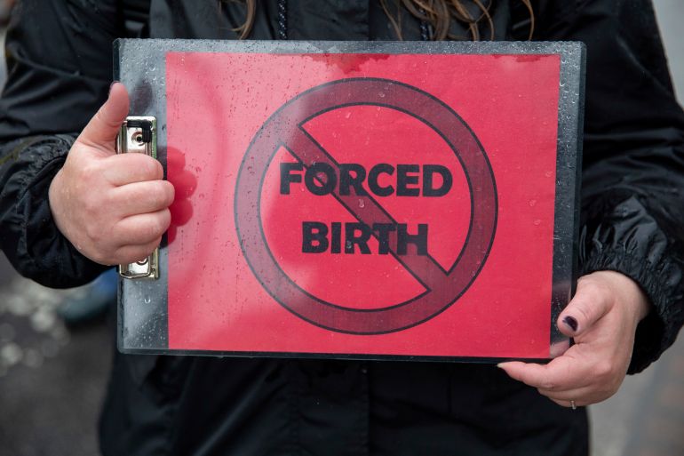 A protester holds up a sign which reads 'Forced Birth' with a forbidden symbol over it as pro abortion-rights demonstrators protest outside of the US Supreme Court.