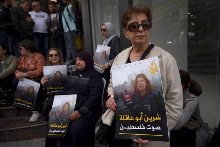 Palestinian mourners carry pictures of slain Al Jazeera journalist Shireen Abu Akleh with words in Arabic that read: 'Shireen, the voice of Palestine'.