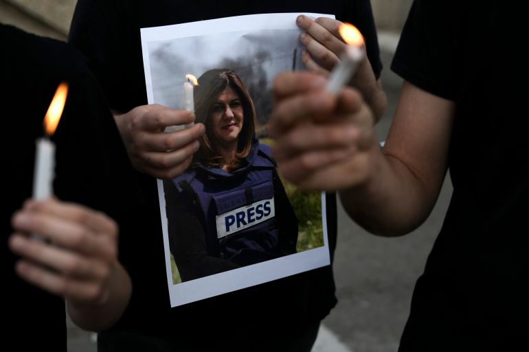Protesters hold candles and a photo of slain Al Jazeera journalist Shireen Abu Akleh