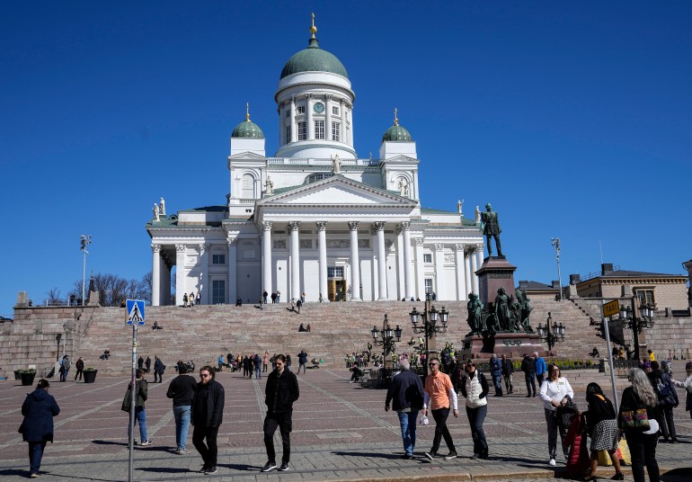 People walk at the Helsinki Cathedral under a blue sky in the city center of Helsinki, Finland, Friday, May 13, 2022.
