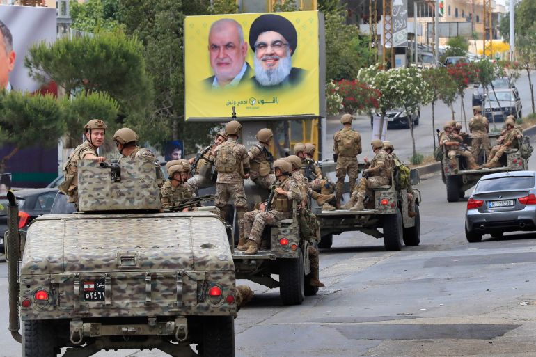 Lebanese army patrol past a poster showing portraits of Hezbollah leader Hassan Nasrallah, right, and the head of Hezbollah's parliamentary bloc, Mohammed Raad, in Nabatiyeh, south Lebanon