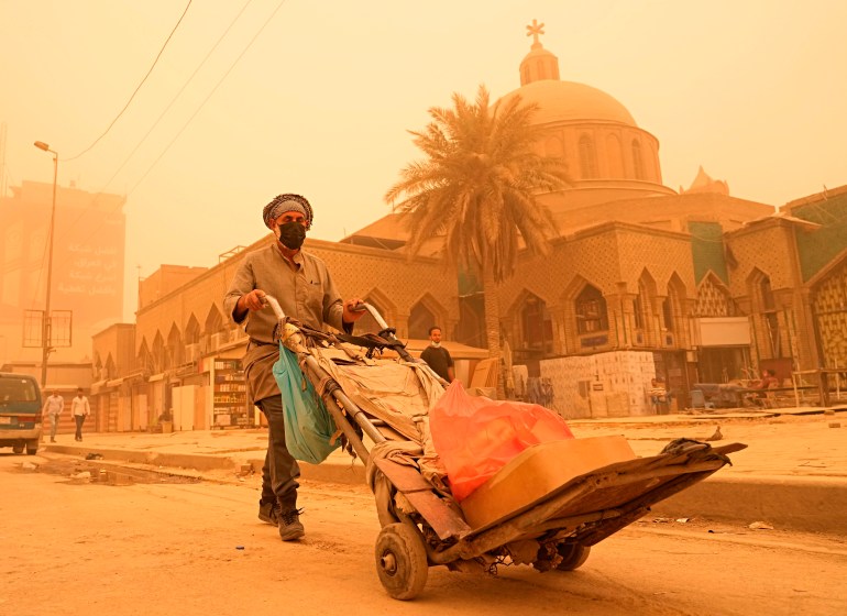 A man pushes a cart during a sandstorm in Baghdad, Iraq