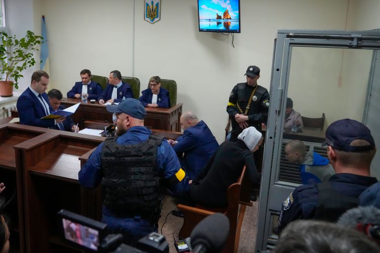 Sitting behind a glass, Russian army Sergeant Vadim Shishimarin, 21, talks with his translator, centre right, during a court hearing in Kyiv, Ukraine,