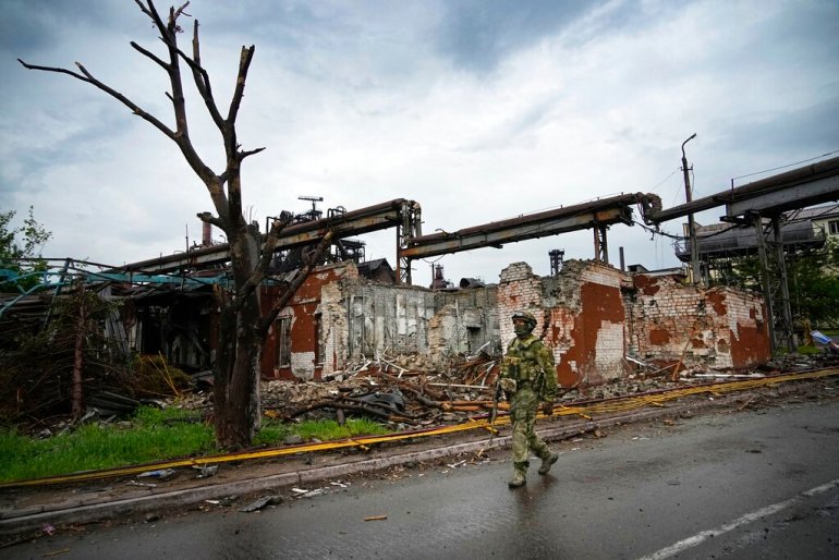 A Russian soldier walks past a destroyed part of the steel mill in Mariupol, Ukraine.
