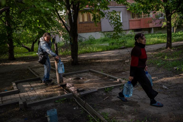 Residents of a shelled neighbourhood collect water from a public water pump in Kharkiv, eastern Ukraine, Thursday, May 19, 2022.