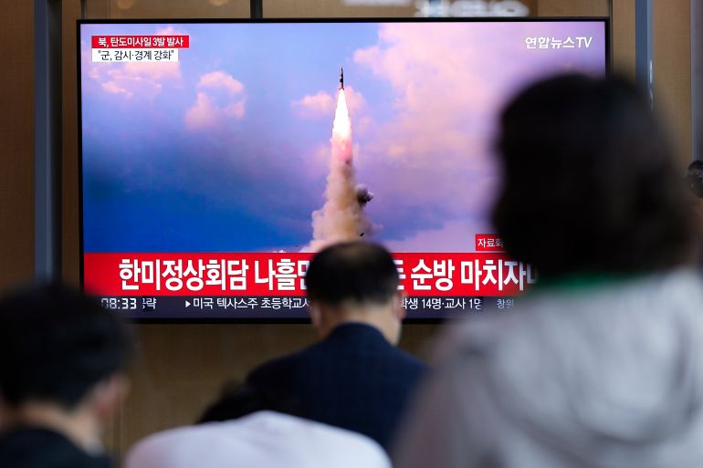 People watch a TV screen showing a news program reporting about North Korea's missile launch with file image, at a train station in Seoul