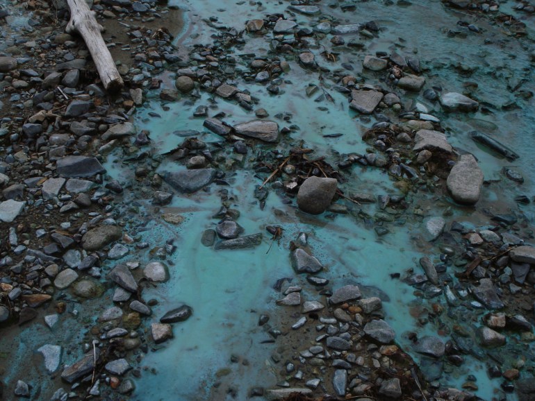 The polluted river near the mine has turned a glowing turquoise