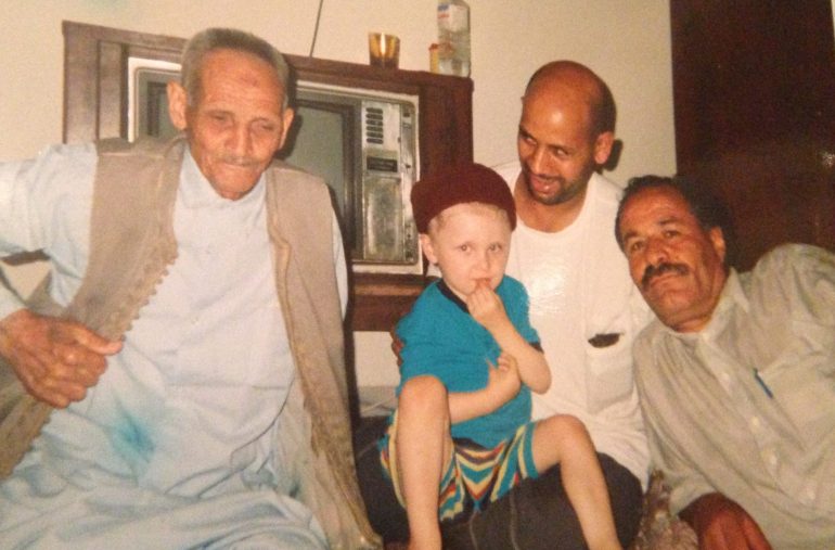 a photo of the author's brother with their grandfather, father and uncle, on a carpet in the Libya home