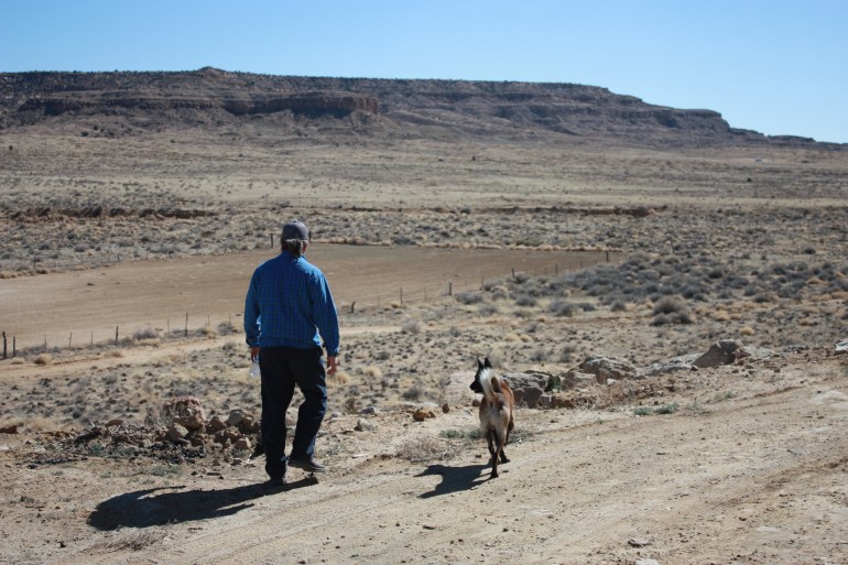 A farmer walks towards his field, with his dog